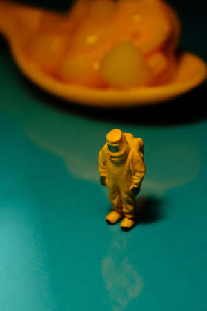 Team of miniature hazmat men inspect spoonful of mac and cheese for food safety symbolismの写真素材