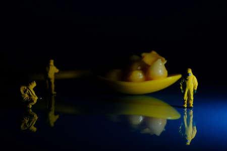 Team of miniature hazmat men inspect spoonful of mac and cheese for food safety symbolismの写真素材