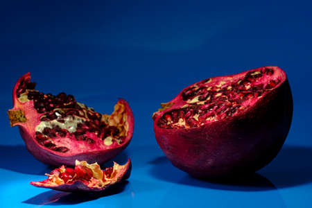 Peeled natural organic pomegranate on blue studio backgroundの写真素材