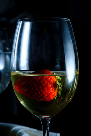Romantic date at fancy restaurant with pinot grigio white wine with strawberry floating in glassの写真素材