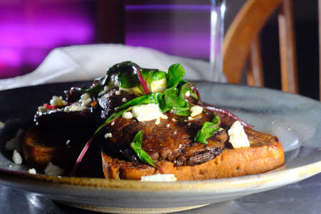 Open faced portobello mushroom sandwich on toast with feta cheese and garnished with sauteed chardの写真素材