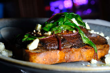 Open faced portobello mushroom sandwich on toast with feta cheese and garnished with sauteed chardの写真素材