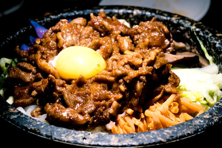 Korean hot spicy pork bibimbap served in heated stone bowlの写真素材