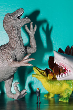 Toy dinosaurs and shark bullying and laughing at poor sad businessmanの写真素材