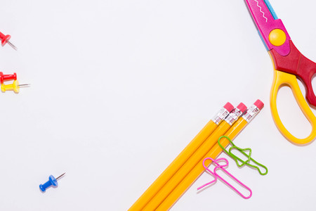 Two paper clips talking while lying on a white floor and on a pencil. Miniature school life and back to school concept with copy space white background.の写真素材