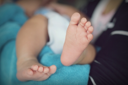 Photo of newborn baby feet and hand in soft focusの写真素材