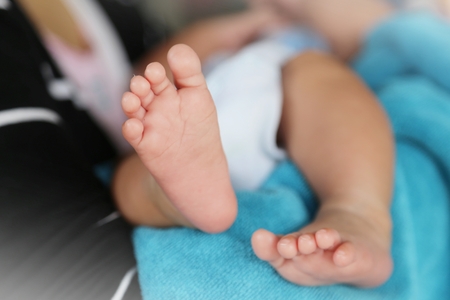 Photo of newborn baby feet and hand in soft focusの写真素材