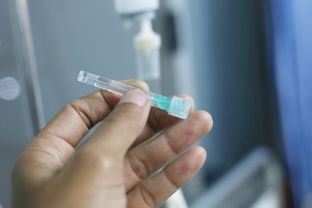 old woman's hand is on a drip receiving a saline solution.の写真素材
