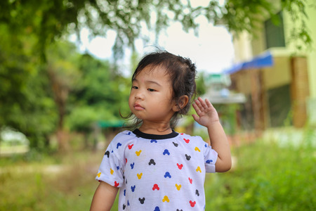 girl playing with bear doll under the tree and eating bananaの写真素材