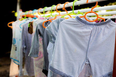 Dressing closet with complementary clothes arranged on hangers.Colorful wardrobe of newborn,kids,...