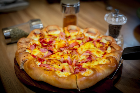Close up of pizza on the wooden table with spices and garnishの写真素材