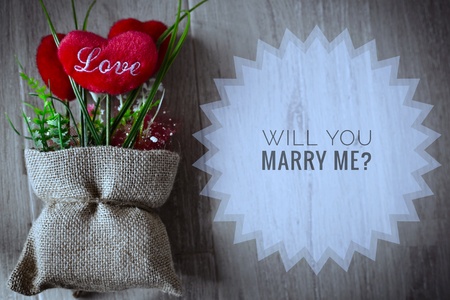 Will you marry me? words on red heart in small sacks and wooden backgroundの写真素材