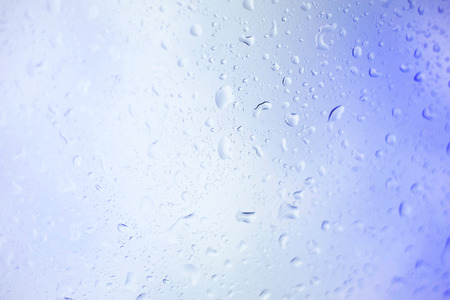 Water drops on glass, rain drop background defocused on blue surface.