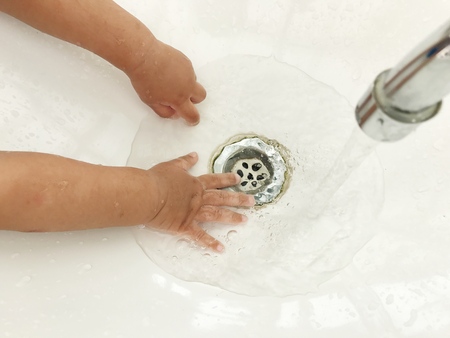 Child's hand playing water in basin.の写真素材
