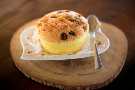 Vanilla cupcake with raisin on top, put on wooden plate.の写真素材