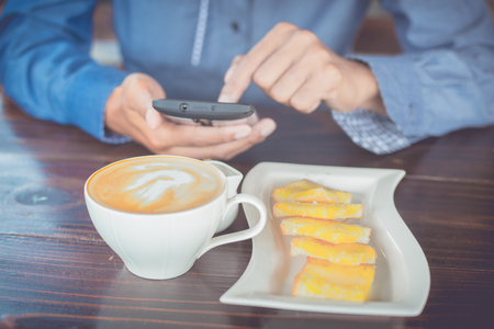 Business man using mobile phone during coffee in the morning.の写真素材