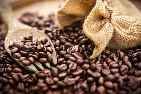 Coffee beans and wooden spoon on sackcloth surfaceの写真素材