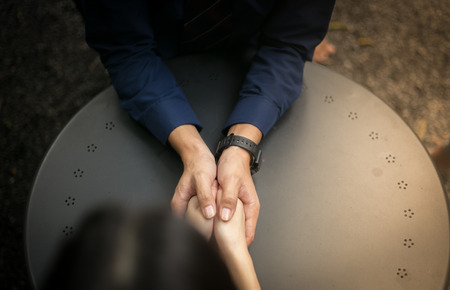 Man holding a woman's hand inside his two hands.の写真素材