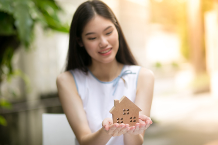 Beautiful woman holding a small wooden house, thinking.の写真素材