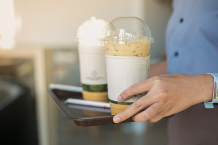 Woman hand's Barista holding ice coffee serving customer.