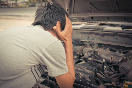 frustrated man stand front of a broken car needs assistance with opened hood, a difficult situation.の写真素材