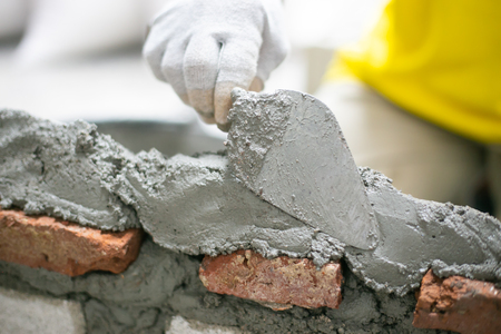 Close up of industrial bricklayer installing bricks on construction site, building walls.の写真素材