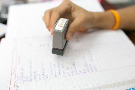 hand catching rubber stamp on account book background.