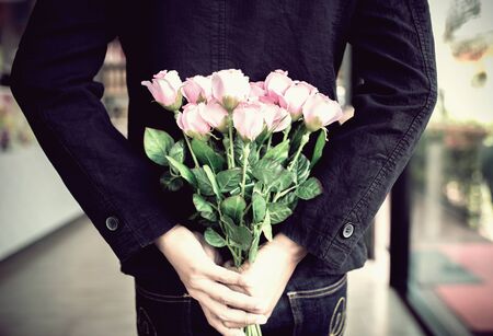 Man holding pink bouquet of roses on back, Surprise special time.の写真素材