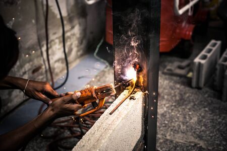 Industry worker welding iron pieces at work. Man hand iron welding at manufacturing.
