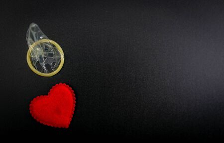 Condom and red heart on black background, Safe sex or Valentine's day concept.の写真素材