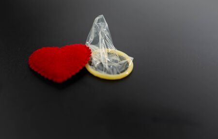 Condom and red heart on black background, Safe sex or Valentine's day concept.の写真素材