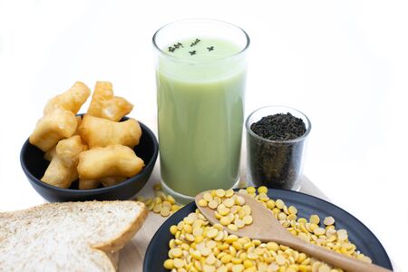 A glass of green tea and soy milk. Matcha soybean milk in glass and on white wood table. A healthy veggie drink.の写真素材