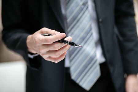 Businessman holding a pen, Men in black suit.の写真素材
