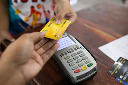 Hand using credit card with NFC technology in a supermarket close up.