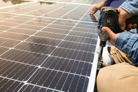 Male technician installing photovoltaic solar modules with screw. Man electrician panel sun sustainable resources renewable energy source alternative innovation.の写真素材