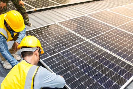 Male technician installing photovoltaic solar modules with screw. Man electrician panel sun sustainable resources renewable energy source alternative innovation.の写真素材