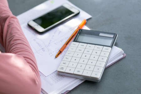 Business Meeting Scene, calculator, orange pen and report on a desk.の写真素材