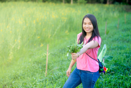Portrait of asian teen girl holding flower in the field.の写真素材