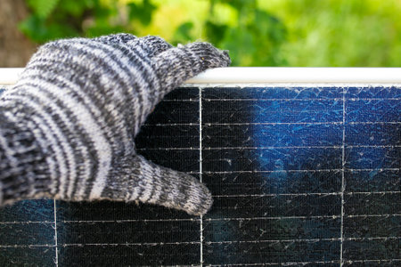 Hand in woolen glove on the background of a solar panel.の写真素材