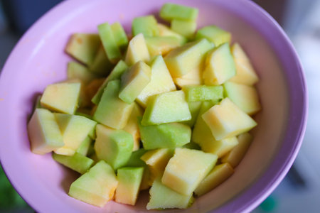 Slices of melon in a bowl on a table.の写真素材