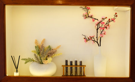 Decorative vase with flowers and candles on the shelf in the roomの写真素材