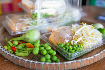 Fried rice noodle with vegetable in plastic box on wooden tableの写真素材