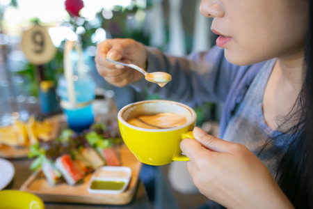 Close up of a beautiful asian woman drinking coffee in a cafeの写真素材