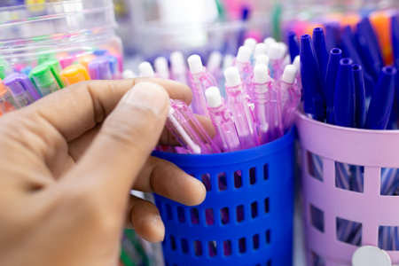 Colorful pens in a plastic basket held by a man's hand