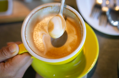 A cup of cappuccino with a spoon in the handの写真素材