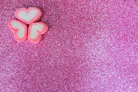 Pink heart shaped marshmallow on pink glitter background with copy space.の写真素材