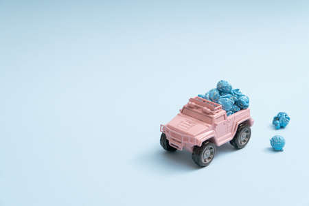 Cute pale pink toy truck delivering popcorns on a pastel blue background minimal with copyspaceの写真素材