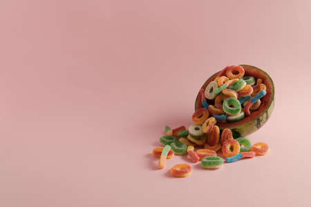 Watermelon half full of colorful gummy candies on a pastel pink background with copyspaceの写真素材