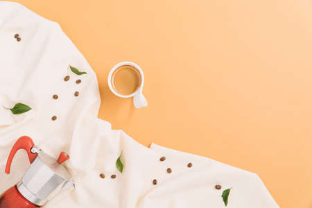 Coffee pot and coffee cup with beans and green leaves. Creative flat lay.の写真素材