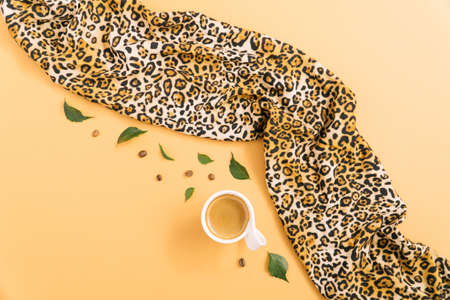 Black espresso coffee in a cup with leaves and coffee beans. Leopard wild animal print scarf.の写真素材
